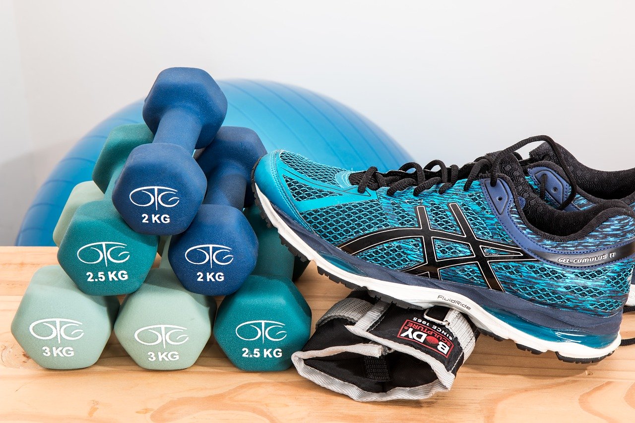 dunbbells, fitness shoes, and other fitness gear piled together, ready to workout